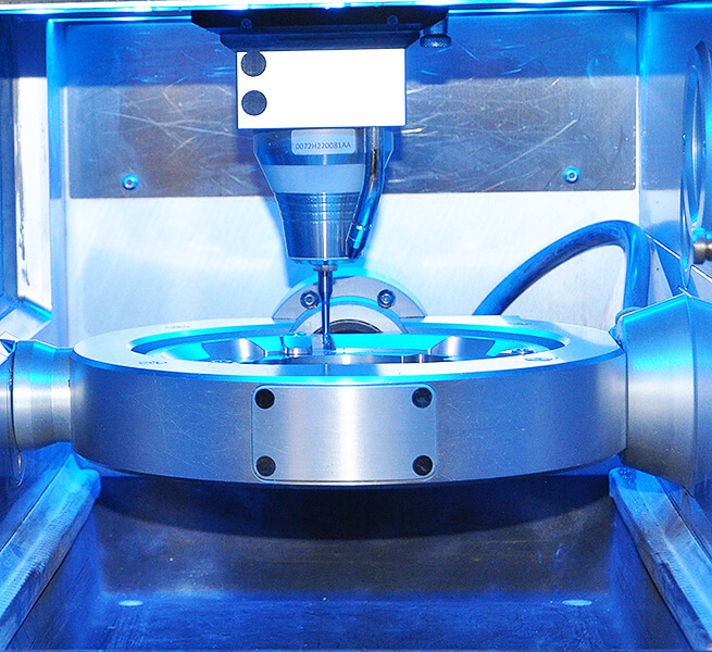 Nahaufnahme einer blau beleuchteten CAD-CAM-Fräsmaschine mit Fräswerkzeug im Arbeitsraum.